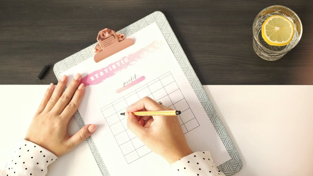 Hands writing a checklist in a planner with a pen