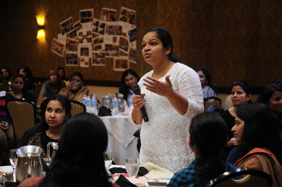Person speaking confidently in front of a small group indoors