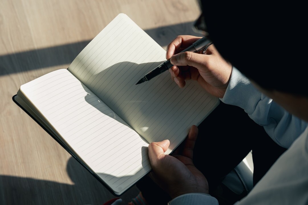 Close-up of hands writing in a notebook with a pen